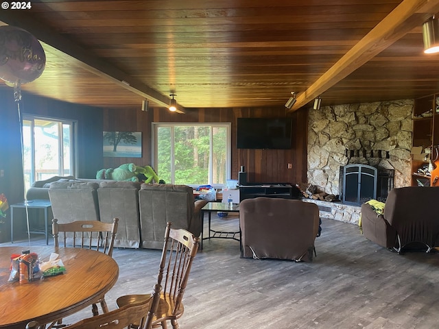 dining room featuring a stone fireplace, wooden ceiling, hardwood / wood-style flooring, wooden walls, and beamed ceiling