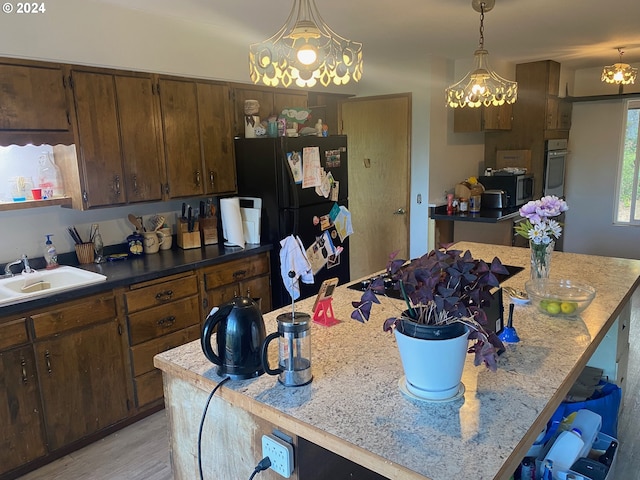 kitchen featuring appliances with stainless steel finishes, a kitchen island, sink, and hanging light fixtures