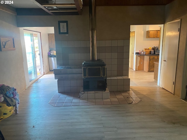 living room with light hardwood / wood-style floors, tile walls, and a wood stove