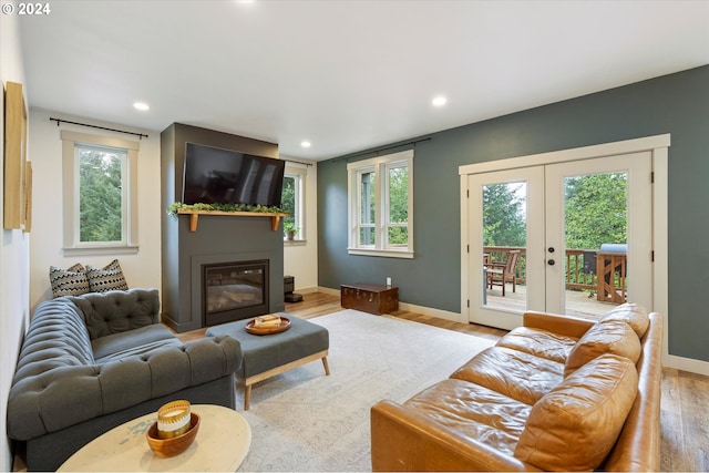 living room with a wealth of natural light, french doors, and light hardwood / wood-style floors