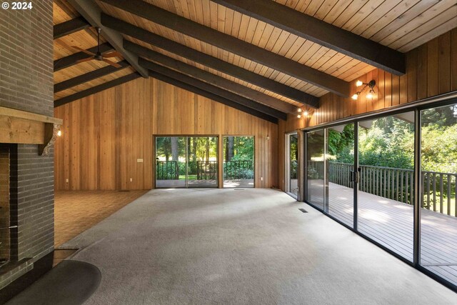 interior space with wooden ceiling, wooden walls, brick wall, beamed ceiling, and carpet