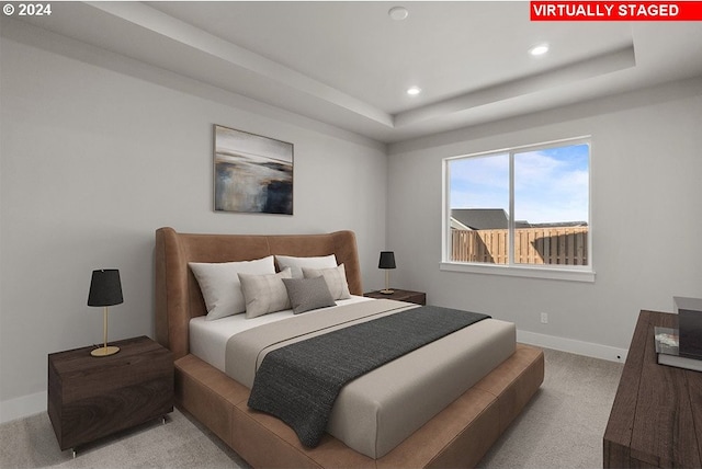 carpeted bedroom with a tray ceiling