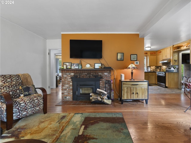 living room featuring wood-type flooring and a brick fireplace