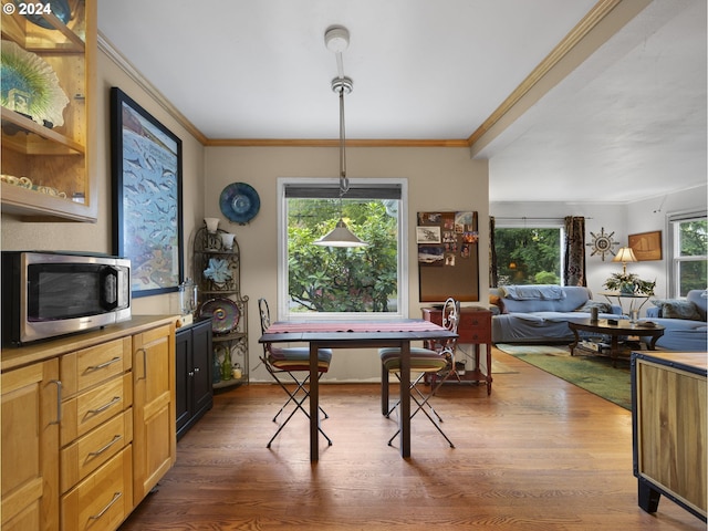 dining area with dark hardwood / wood-style flooring, ornamental molding, and a wealth of natural light