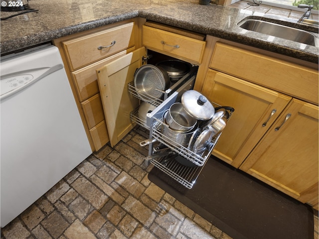 room details with dishwasher, dark stone countertops, and sink