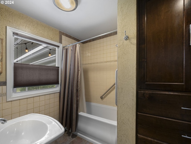 bathroom featuring tile walls, sink, and shower / tub combo