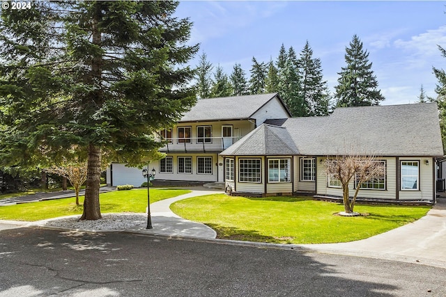 view of front of house featuring a garage, a balcony, and a front yard