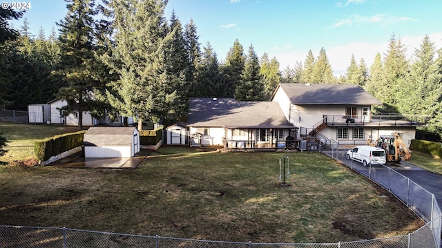 view of front of house featuring a front lawn and a storage shed