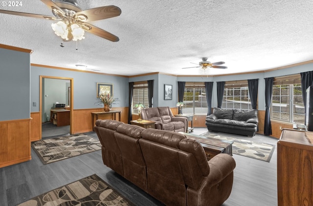 living room with wooden walls, crown molding, ceiling fan, and hardwood / wood-style floors