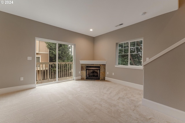 unfurnished living room featuring a tiled fireplace and light carpet