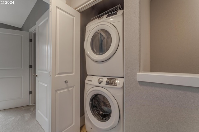 laundry area featuring stacked washer and dryer and light carpet