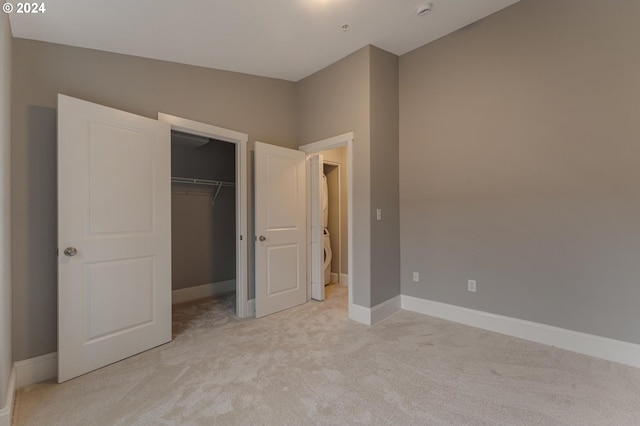 unfurnished bedroom featuring a walk in closet, light colored carpet, and a closet