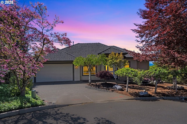 view of front of home with concrete driveway, a tiled roof, and an attached garage