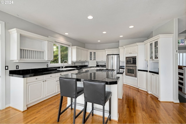 kitchen featuring a kitchen bar, white cabinets, a center island, light hardwood / wood-style floors, and stainless steel appliances