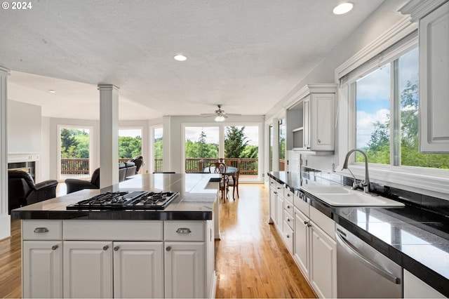 kitchen featuring light hardwood / wood-style floors, stainless steel dishwasher, sink, and white cabinetry