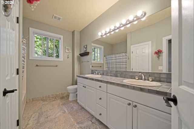 bathroom with vanity, curtained shower, tasteful backsplash, and toilet