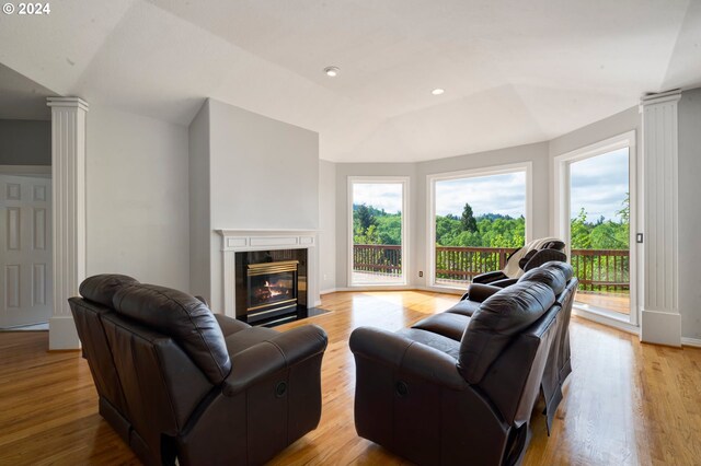 living room with light wood-type flooring, lofted ceiling, and ornate columns