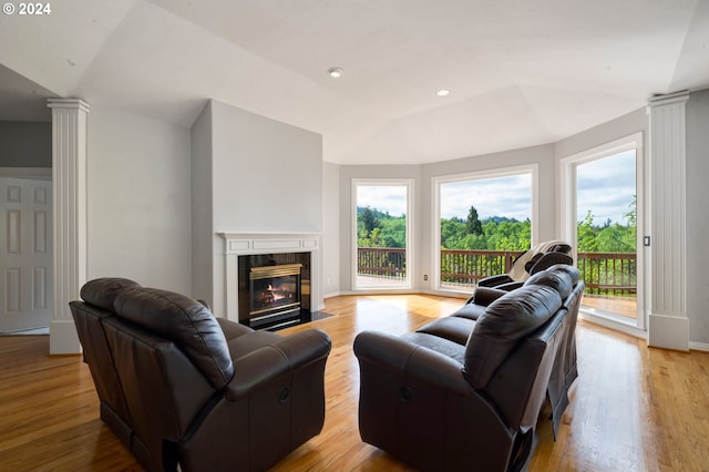 living room featuring a fireplace, light hardwood / wood-style flooring, and decorative columns