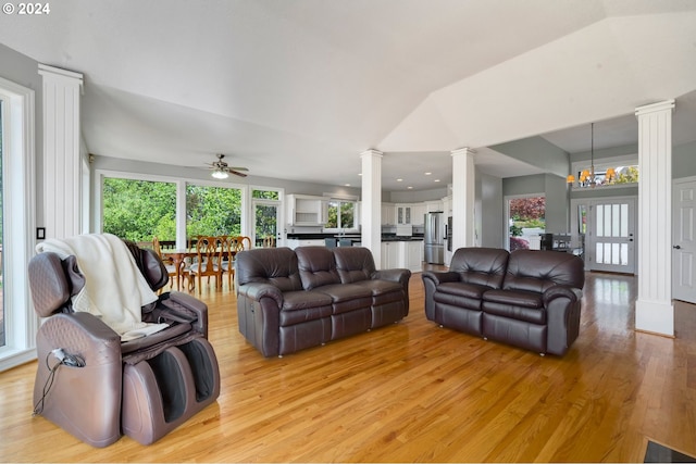 living room with decorative columns, lofted ceiling, ceiling fan with notable chandelier, and light wood-type flooring