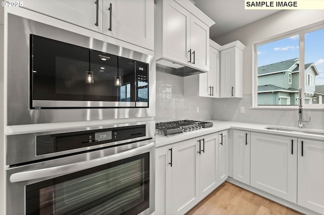1376 NE Josephine Ct Unit 184, Estacada, OR 97023 - kitchen featuring white cabinetry, light wood-style flooring, stainless steel appliances, light countertops, and backsplash
