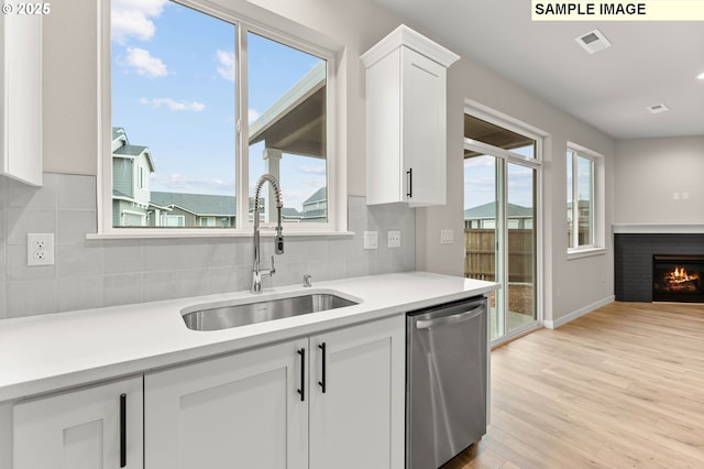 1376 NE Josephine Ct Unit 184, Estacada, OR 97023 - kitchen featuring stainless steel dishwasher, light wood-style flooring, light countertops, a sink, and white cabinetry