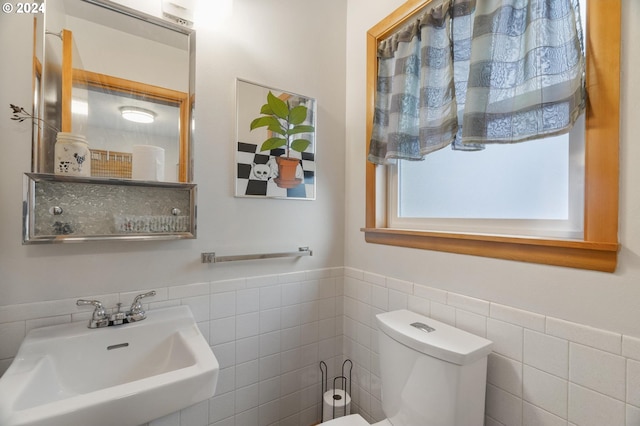 bathroom featuring toilet, sink, and tile walls