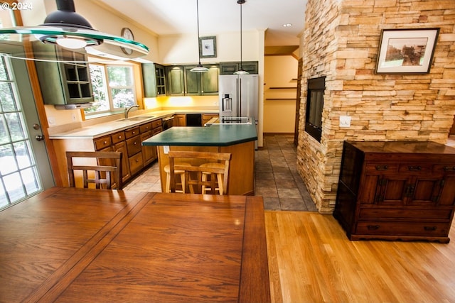 kitchen featuring a center island, black appliances, a stone fireplace, sink, and light hardwood / wood-style flooring