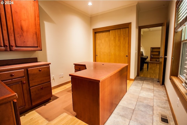 interior space featuring light tile patterned floors, a center island, and ornamental molding