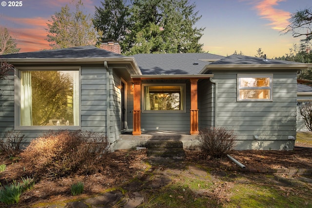 view of front of home with a shingled roof and a chimney