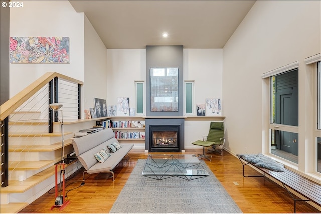 living area with stairway, wood finished floors, a high ceiling, recessed lighting, and baseboards