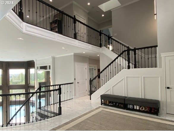 staircase featuring ornamental molding and a towering ceiling