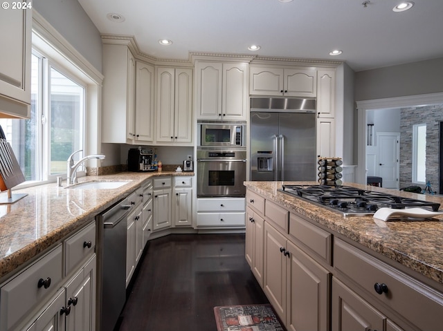 kitchen featuring light stone countertops, sink, built in appliances, and dark hardwood / wood-style flooring