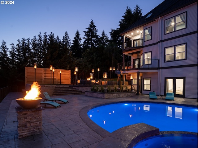 pool at dusk with an in ground hot tub, a patio area, and an outdoor fire pit