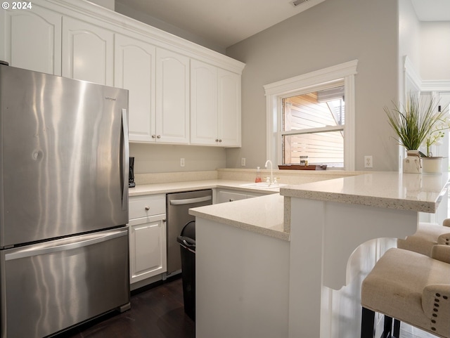 kitchen featuring light stone counters, sink, white cabinets, kitchen peninsula, and stainless steel appliances