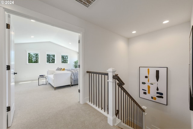 hall with vaulted ceiling and light colored carpet