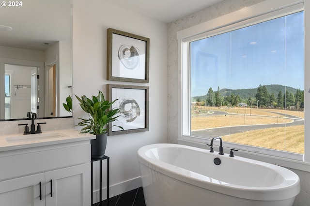 bathroom with a mountain view, vanity, tile patterned floors, and a tub