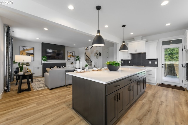 kitchen with light wood-type flooring, decorative light fixtures, backsplash, and white cabinets