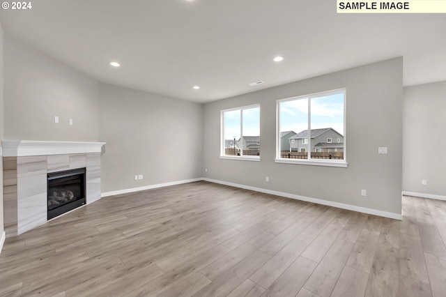 unfurnished living room featuring light wood-type flooring and a tile fireplace