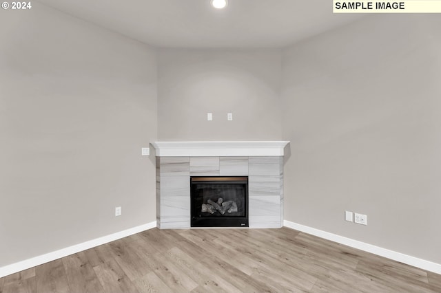 unfurnished living room featuring light hardwood / wood-style floors and a tiled fireplace