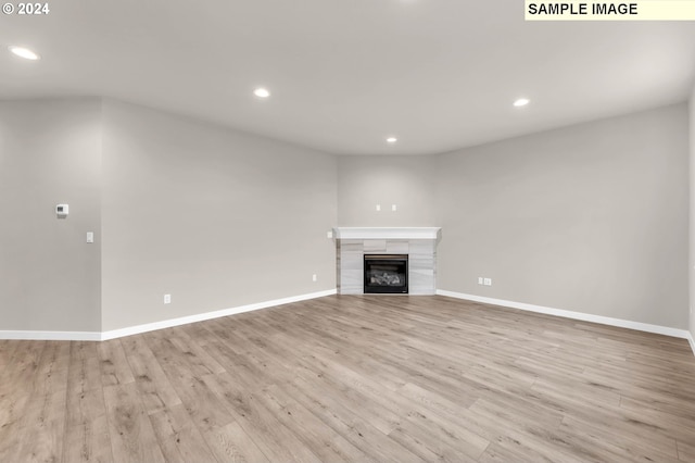 unfurnished living room featuring a tile fireplace and light hardwood / wood-style floors