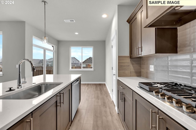 kitchen with sink, light wood-type flooring, decorative light fixtures, stainless steel appliances, and extractor fan