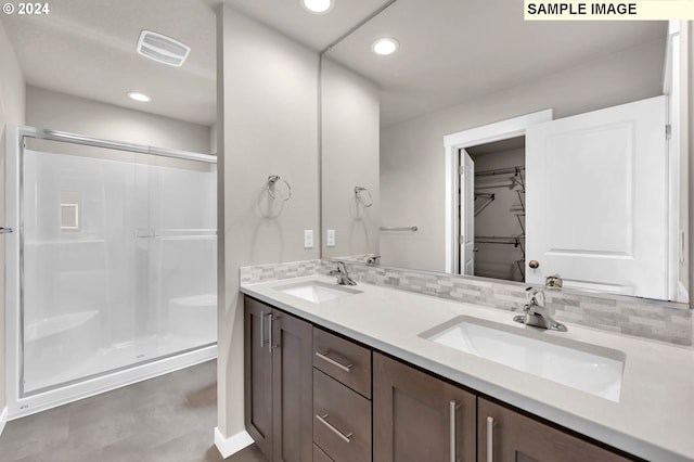 bathroom with decorative backsplash, vanity, and a shower with door