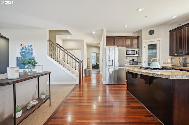 kitchen with plenty of natural light, appliances with stainless steel finishes, backsplash, and dark hardwood / wood-style flooring