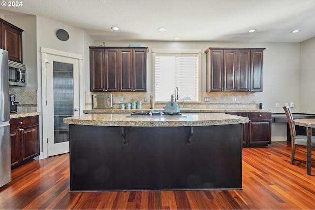 kitchen featuring a kitchen island, a breakfast bar, backsplash, and dark hardwood / wood-style flooring