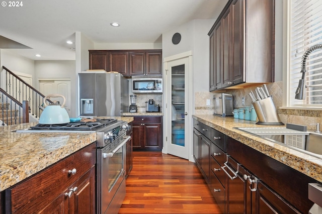 kitchen featuring backsplash, dark hardwood / wood-style flooring, stainless steel appliances, sink, and light stone counters