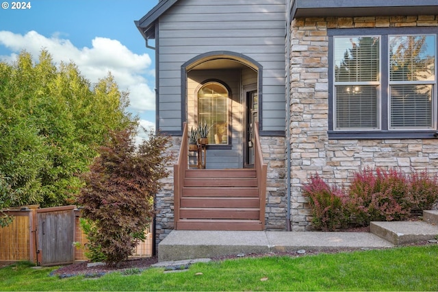 doorway to property with fence and stone siding