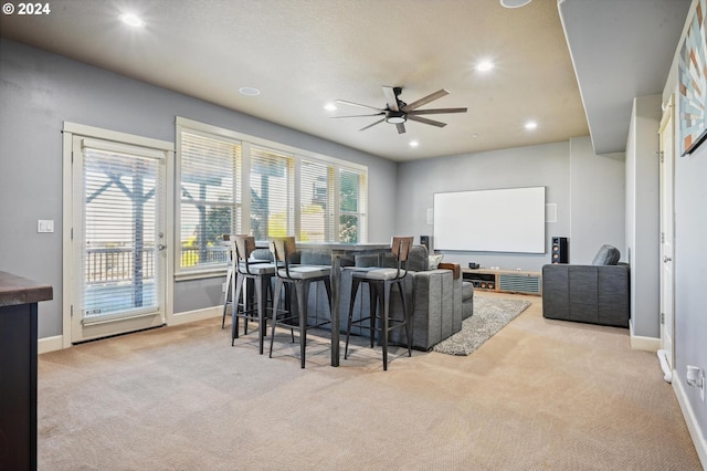 carpeted cinema room featuring bar area and ceiling fan