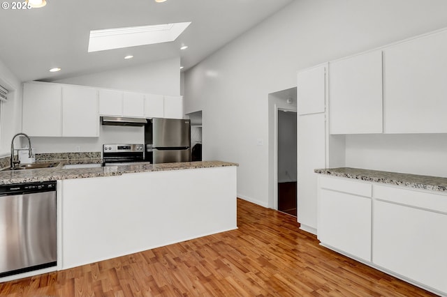 24221 Warthen Rd, Elmira, OR 97437 - kitchen with stainless steel appliances, a sink, under cabinet range hood, a skylight, and white cabinetry