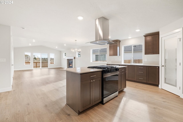 kitchen with lofted ceiling, ventilation hood, light wood-type flooring, a kitchen island, and stainless steel range with gas stovetop