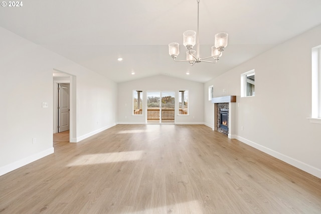 unfurnished living room with a fireplace, a chandelier, lofted ceiling, and light wood-type flooring